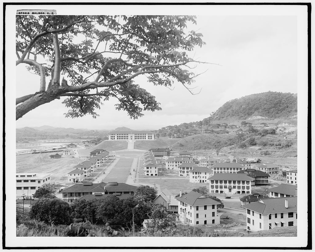 Black and white photograph of uniform white buildings in front of a hill