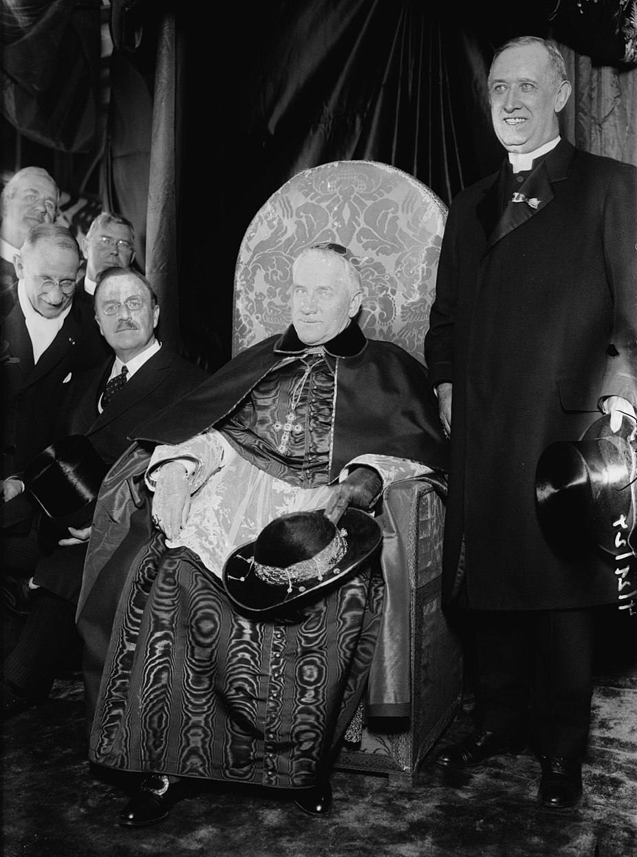 Black and white photograph of Cardinal Hayes seated on a chair, with Bishop Dunn standing to the right and   four men standing to the left.